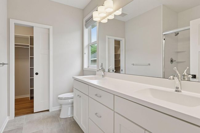 Primary bath features dual vanity, tile flooring, and pocket door leading to closet | Image 27