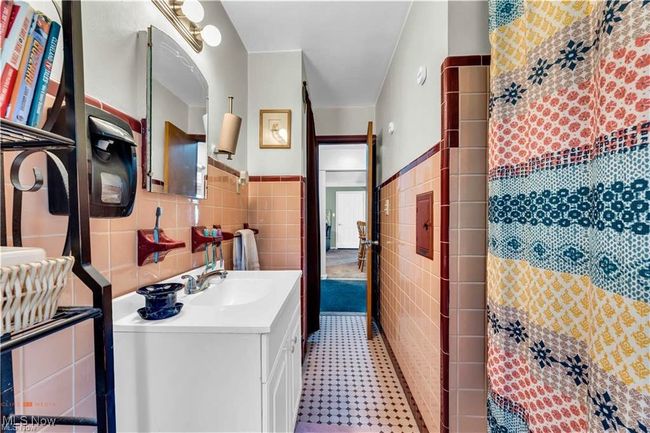Full bathroom with tile walls, vanity, curtained shower, a wainscoted wall, and tile patterned floors | Image 20