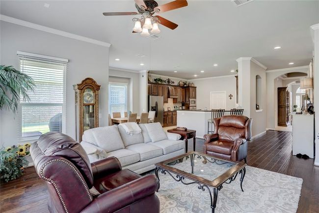 This is a spacious and well-lit living room with an open-plan layout that flows into the kitchen area. Large windows allow for plenty of natural light. | Image 12