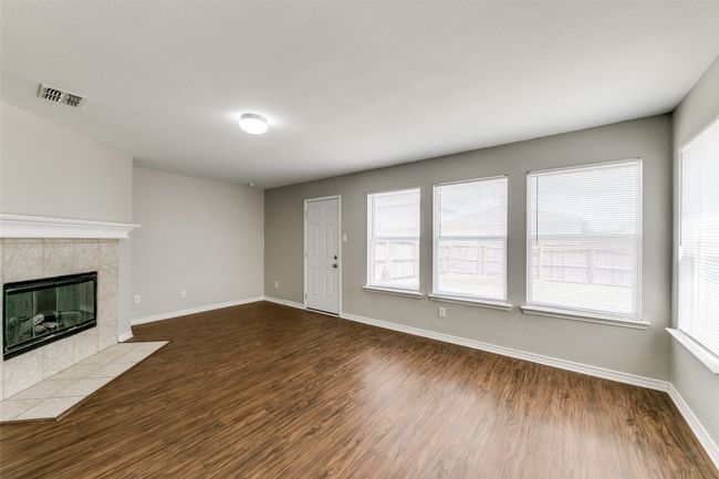 Unfurnished living room with a tiled fireplace, a healthy amount of sunlight, and dark hardwood / wood-style flooring | Image 9