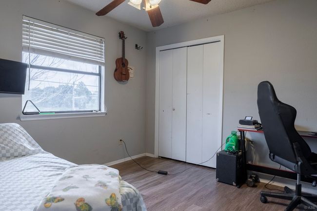 Bedroom featuring wood finished floors, an office area, a closet, a ceiling fan, and baseboards | Image 23