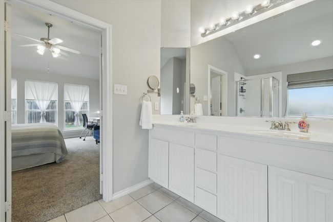 Bathroom featuring double vanity, ceiling fan, vaulted ceiling, a stall shower, and connected bathroom | Image 25