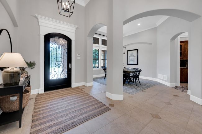 Entryway with crown molding, light tile patterned floors, a high ceiling, baseboards, and a chandelier | Image 9