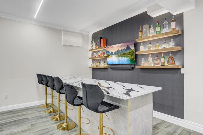 Indoor dry bar featuring light wood-style floors, baseboards, and ornamental molding | Image 28