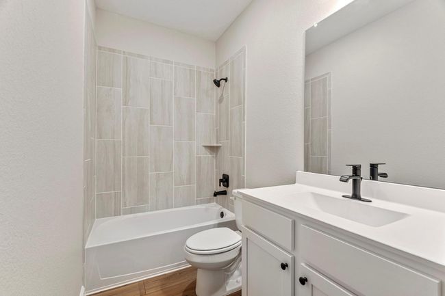 The secondary bathroom has a large tub and shower combo, which is perfect for relaxing in a hot bath or taking a refreshing shower. It also has a large vanity and sink, which provides ample storage space for toiletries and other personal items. | Image 13