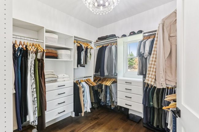 Spacious closet featuring dark wood-style floors and a chandelier | Image 25