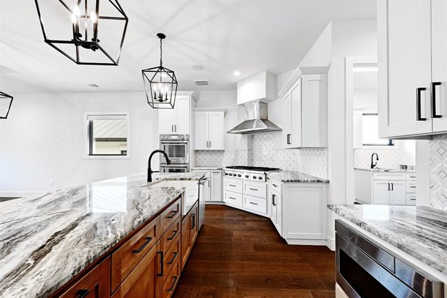 Kitchen with visible vents, an inviting chandelier, white cabinets, appliances with stainless steel finishes, and wall chimney range hood | Image 12