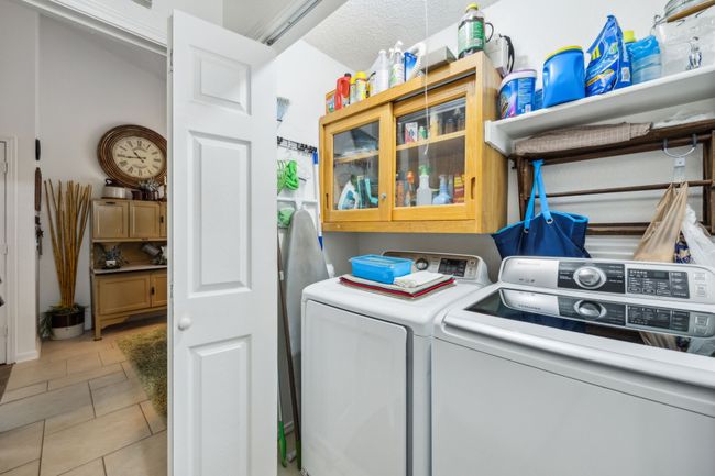 Washroom featuring washer and clothes dryer, light tile patterned flooring, and cabinet space | Image 16