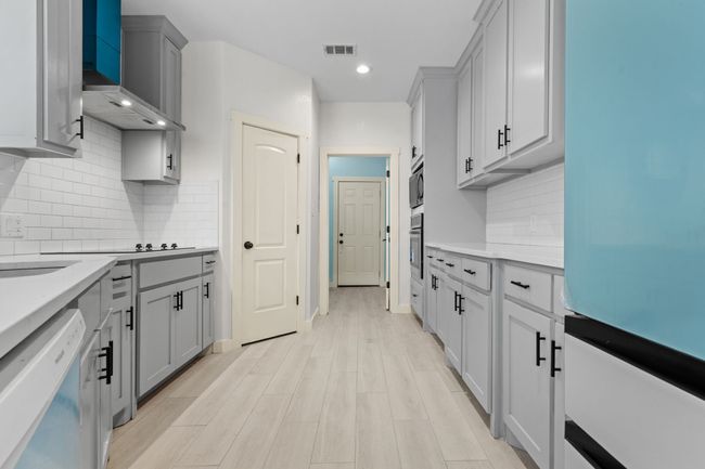 Kitchen with white dishwasher, fridge, wall chimney exhaust hood, a warming drawer, and gray cabinetry | Image 14