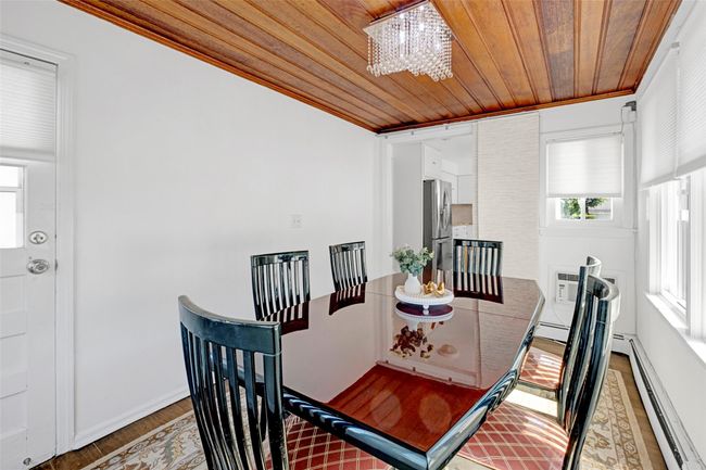 Dining space with a baseboard heating unit, wooden ceiling, a chandelier, light wood-style flooring, and a wall mounted AC | Image 11