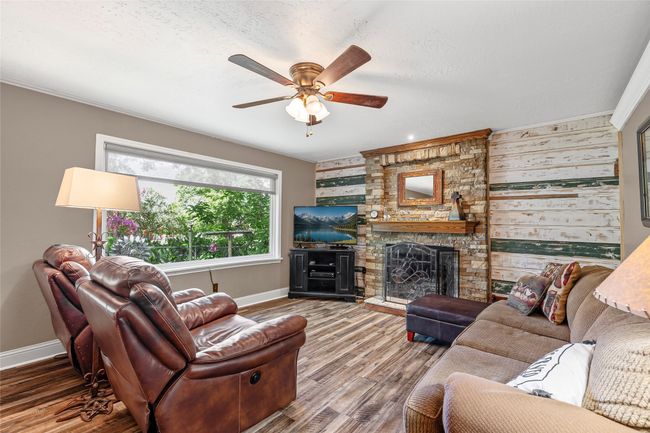 Living area featuring a ceiling fan, wood finished floors, and a fireplace | Image 12