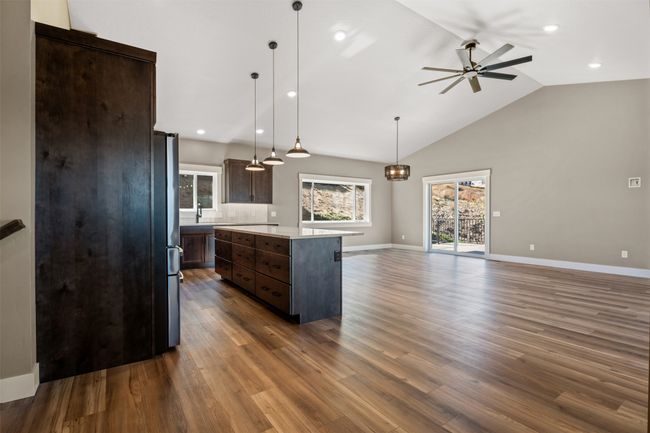 Kitchen with dark brown cabinets, light countertops, ceiling fan, a center island, and lofted ceiling | Image 19