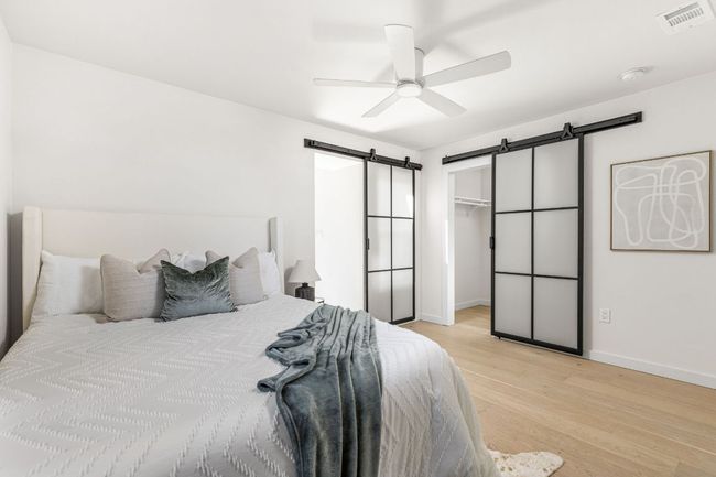 Bedroom with a barn door, light wood-style flooring, ceiling fan, and a walk in closet | Image 26