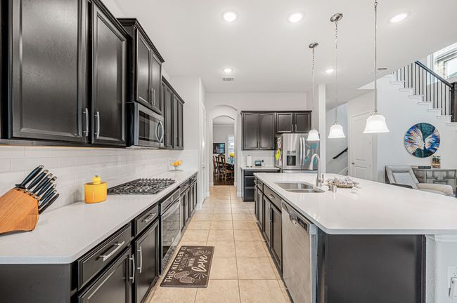 Kitchen with stainless steel appliances, a kitchen island with sink, arched walkways, and tasteful backsplash | Image 12