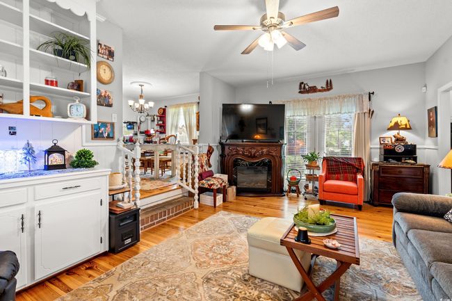 Living area featuring plenty of natural light, light wood finished floors, ceiling fan, and a chandelier | Image 9