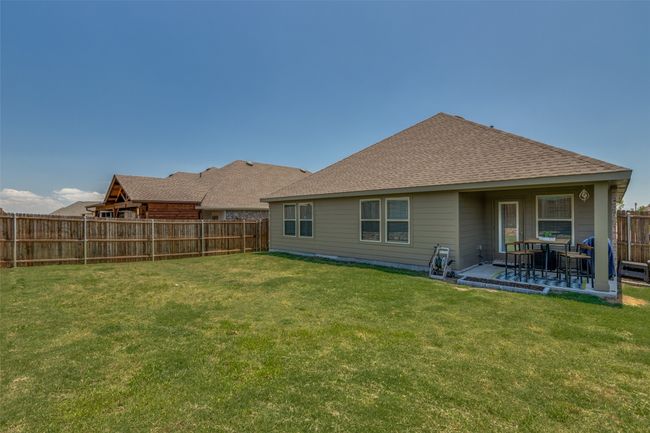 Rear view of property with a shingled roof and a covered patio with a spatious yard | Image 23