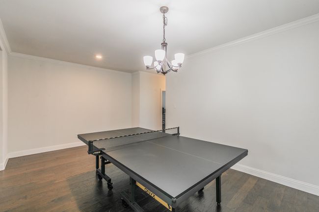Game room featuring dark wood-type flooring, crown molding, baseboards, and a chandelier | Image 37