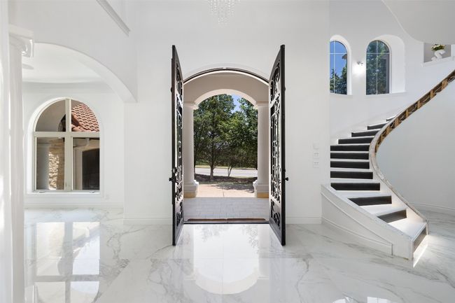 Foyer entrance with marble tiled flooring, a high ceiling, arched walkways, stairway, and baseboards | Image 5