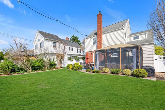 Back of property featuring a chimney, roof with shingles, a sunroom, and a yard | Image 16