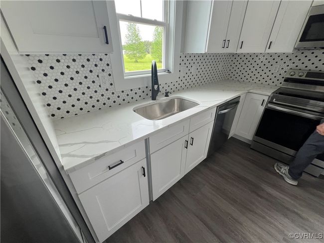 Kitchen with white cabinetry, stainless steel appliances, a sink, and dark wood-type flooring | Image 10