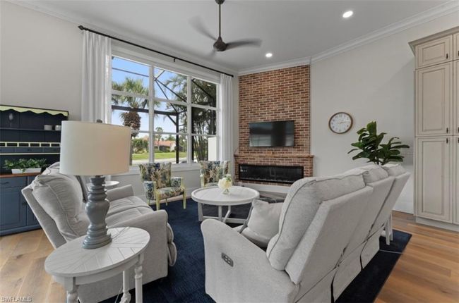 Living area featuring a fireplace, light wood finished floors, recessed lighting, ornamental molding, and ceiling fan | Image 13