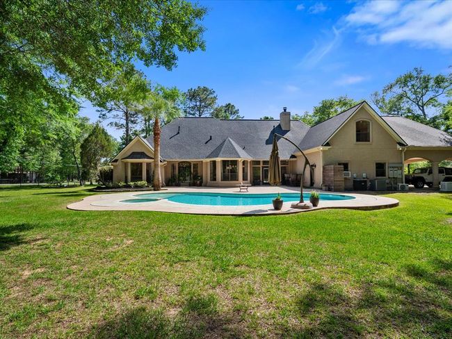 By day, the backyard shines just as bright—featuring wide-open green space, mature trees, and a sparkling pool as the centerpiece. | Image 40