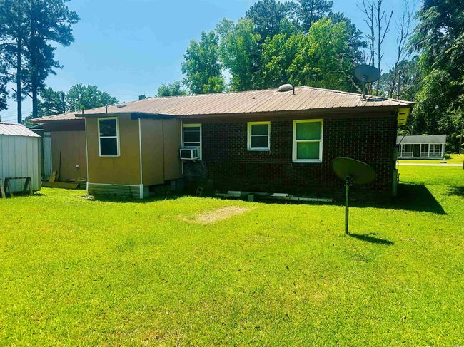 Rear view of house with a yard, cooling unit, brick siding, and metal roof | Image 22