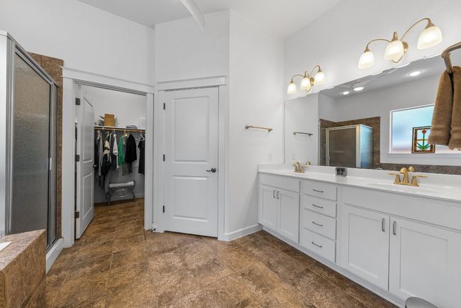 Full bath with a shower stall, double vanity, a sink, and a walk in closet | Image 18