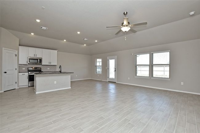 Kitchen with open floor plan, vaulted ceiling, white cabinets, stainless steel appliances, and a sink | Image 9
