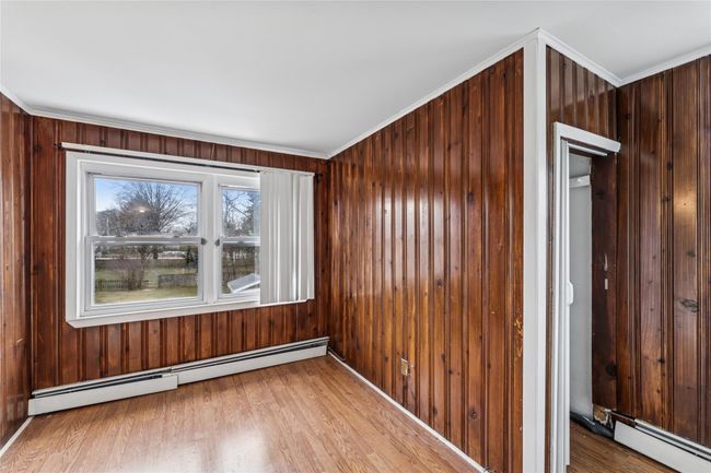 Spare room with wood finished floors, ornamental molding, wooden walls, and baseboard heating | Image 12