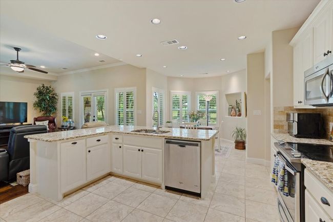 Kitchen featuring appliances with stainless steel finishes, a sink, open floor plan, a ceiling fan, and white cabinets | Image 9
