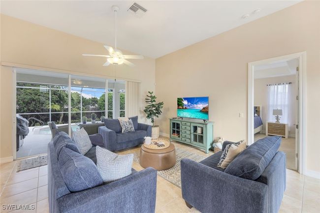Tiled living room featuring ceiling fan and lofted ceiling | Image 4