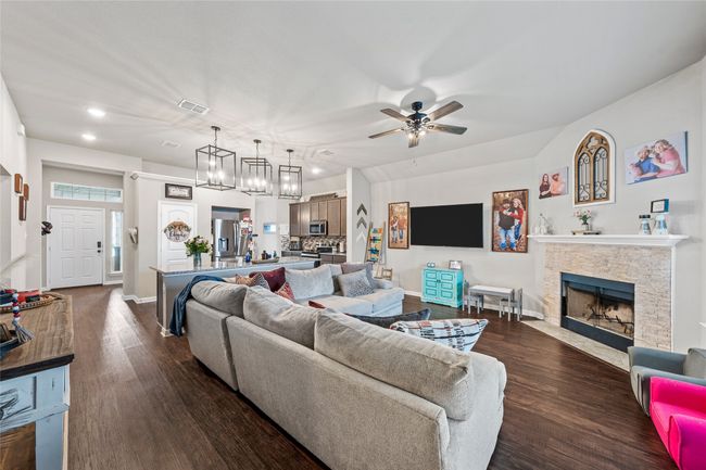 Living area with dark wood finished floors, ceiling fan, a fireplace with flush hearth, recessed lighting, and baseboards | Image 14