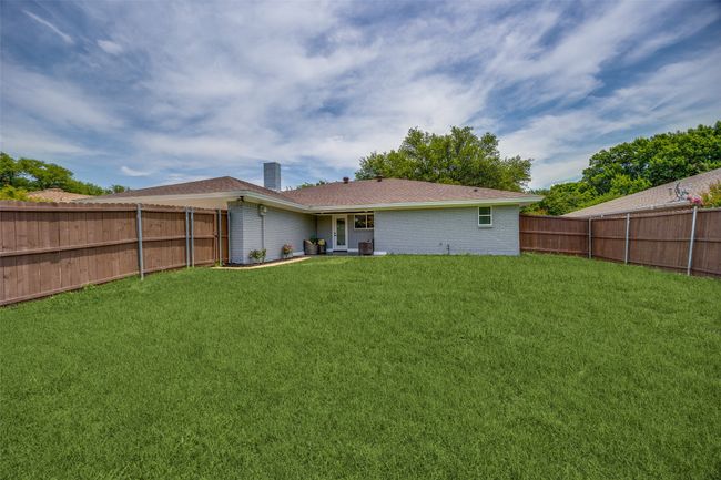 Rear view of house with a chimney, a fenced backyard, and brick siding | Image 34