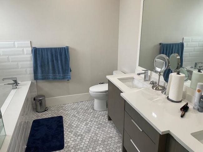 Bathroom with tile patterned floors, vanity, a relaxing tiled tub, baseboards, and toilet | Image 11
