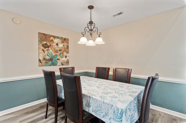 Dining space with wood finished floors and a chandelier | Image 15