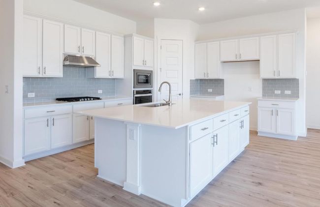 Kitchen featuring under cabinet range hood, a sink, light wood-style floors, white cabinetry, and recessed lighting | Image 8