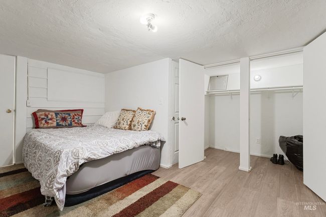 Bedroom with two closets, light wood-style flooring, and a textured ceiling | Image 15