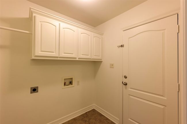 Laundry area featuring electric dryer hookup, baseboards, washer hookup, and cabinet space | Image 8