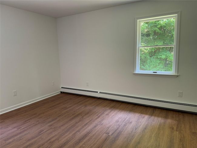 Unfurnished room with wood finished floors, healthy amount of natural light, and a baseboard heating unit | Image 10