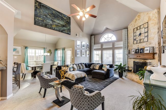 Living room featuring carpet flooring, ceiling fan, a fireplace, and high vaulted ceiling | Image 9