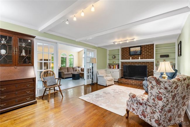 Living room featuring light wood-style flooring, rail lighting, a fireplace, and beamed ceiling | Image 22