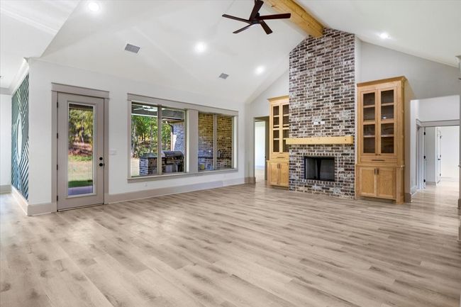 Unfurnished living room with beamed ceiling, a ceiling fan, high vaulted ceiling, light wood-style flooring, and a fireplace | Image 8