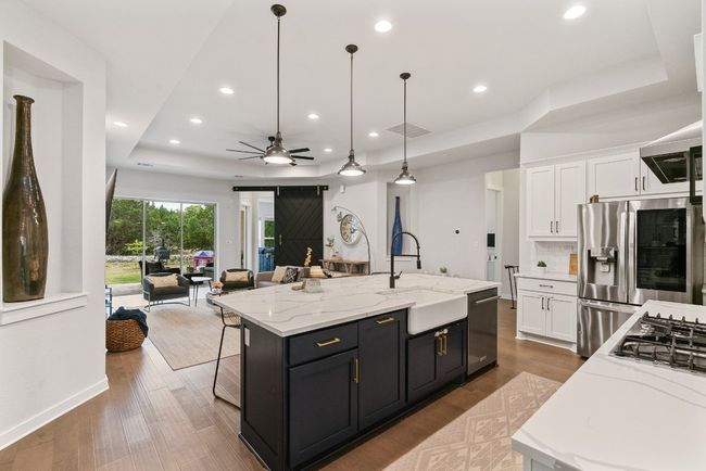 Kitchen with a tray ceiling, open floor plan, white cabinetry, ceiling fan, and recessed lighting | Image 11