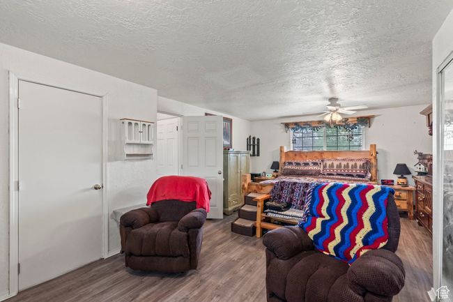 Living room with wood finished floors, a ceiling fan, and a textured ceiling | Image 15