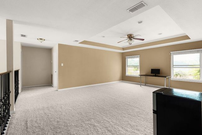Unfurnished living room featuring visible vents, baseboards, a tray ceiling, and light colored carpet | Image 19