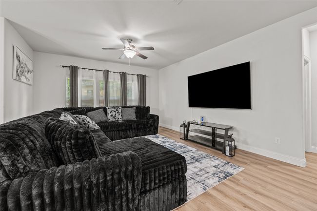 Living area with a ceiling fan, baseboards, and light wood-style floors | Image 8