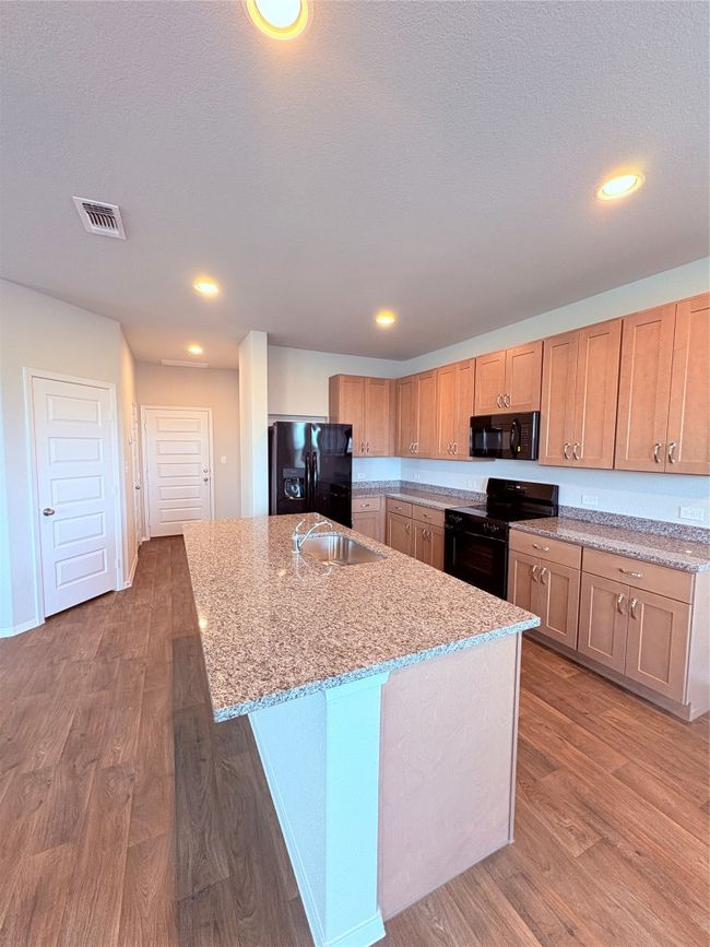 Kitchen featuring light wood-style flooring, a sink, visible vents, stove, and refrigerator | Image 6