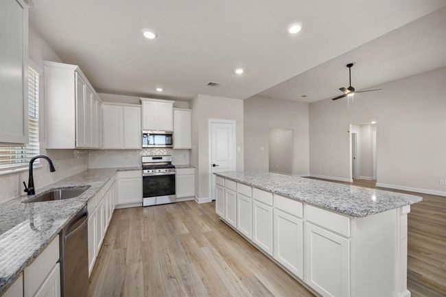 Seamlessly integrated into the overall design scheme of the home, the open kitchen island fosters a sense of continuity and harmony between the kitchen and family room, enhancing the flow of space and promoting a unified aesthetic appeal. | Image 4