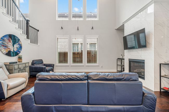Living room with a high end fireplace, a towering ceiling, wood finished floors, and a abundant amount of sunlight | Image 18